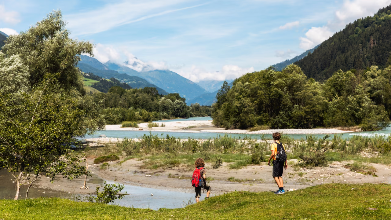Zwei Personen wandern entlang eines Flusses