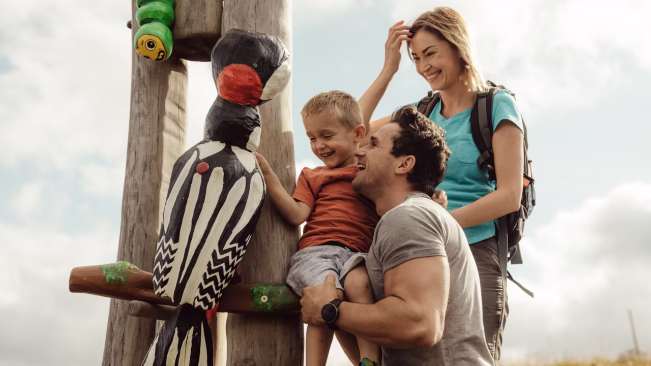 Familienwanderung - Familie steht vor einer Holzfigur